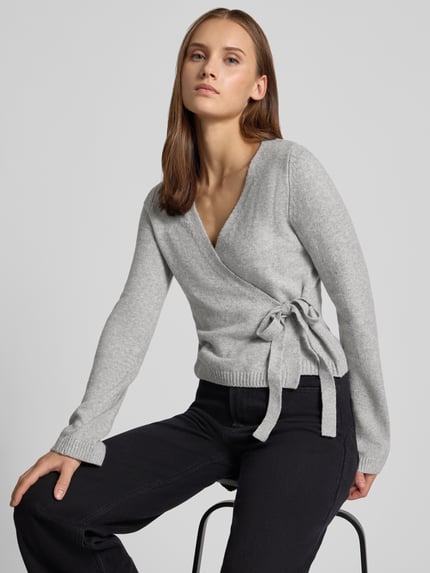 Frauenmodel trägt Strick-Cardigan in Wickeloptik von REVIEW, grau, Material-Mix mit Stretch, V-Ausschnitt, Regular Fit, Nahaufnahme Oberkörper.