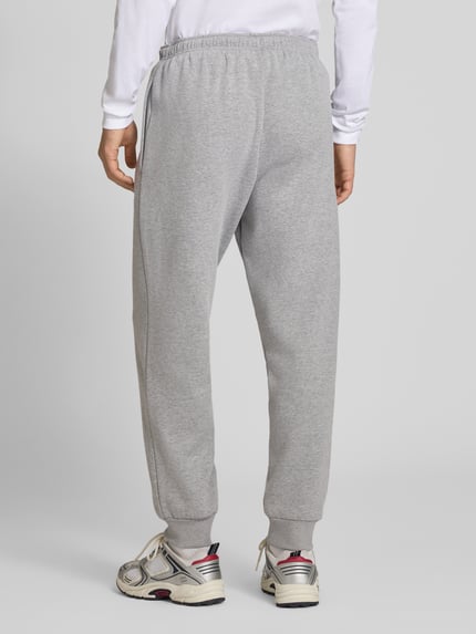 Männermodel trägt Relaxed Fit Sweatpants aus katoenmix Model 'EVOLUTION' van The North Face, grijs met elastische band en zij-steekzakken, Heren sweatpants, binnenbeenlengte maat M 75 cm, Ganzkörperansicht Rückansicht.