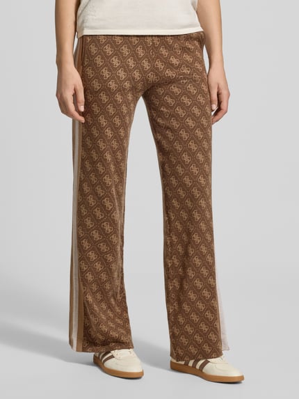 Frauenmodel trägt Wide Leg Strickhose mit Logo-Muster Modell 'ANEIRA' von GUESS, braun, elastischer Bund, Allover-Look, Nahaufnahme Unterkörper. Damen Strickhose aus Material-Mix mit Woll-Anteil, seitlicher Einsatz.