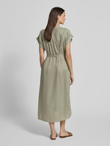 Frauenmodel trägt Hemdblusenkleid aus Leinen mit Bindegürtel Modell 'AMATISTA' von ECOALF, Midikleid in hellem Grün, Rückansicht, Ganzkörperansicht.