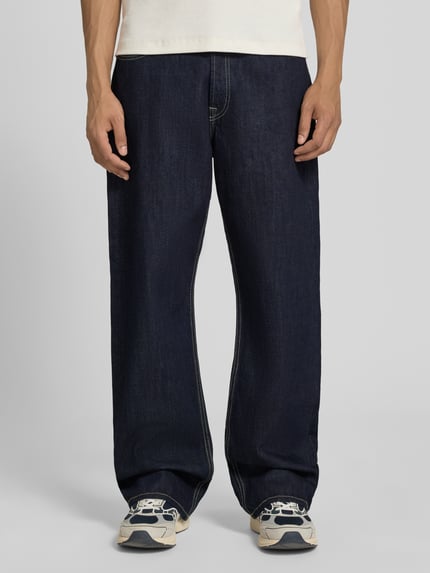 Męski model nosi Loose Straight Fit Jeans mit Eingrifftaschen Modell 'TED' von Jack & Jones z bawełny, ciemnoniebieskie, szerokość w rozmiarze 32/34: 42 cm, długość wewnętrzna nogawki w rozmiarze 32/34: 78 cm, widok całej sylwetki z przodu.