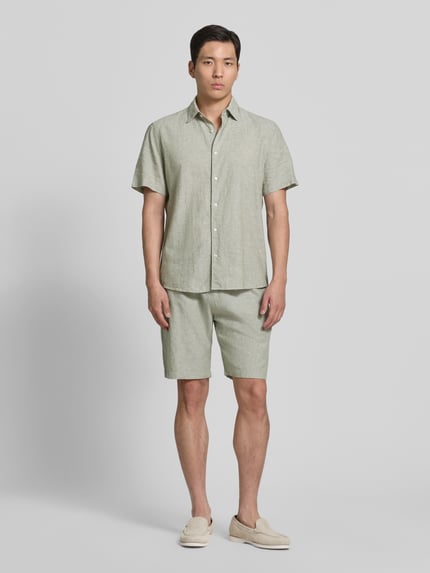 Männermodel trägt Regular Fit Freizeithemd aus Leinen-Baumwoll-Mix von MCNEAL in hellem Grün, Knopfleiste, Kentkragen, Ganzkörperansicht von vorne, Rückenlänge bei Größe M 74 cm, Schulterbreite bei Größe M 50 cm, Ärmellänge bei Größe M 25 cm.