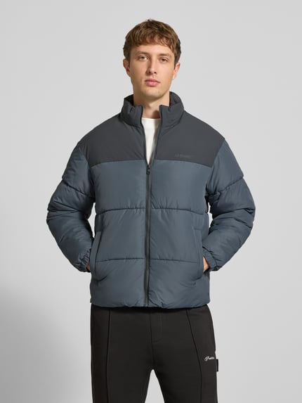 Männermodel trägt Steppjacke mit Stehkragen Modell 'RAZE' von JACK & JONES in Blau mit Reißverschluss, Eingrifftaschen, Ganzkörperansicht von vorne. Rückenlänge 70 cm, Schulterbreite 53 cm, Brustweite 60 cm, Ärmellänge 66 cm, Regular Fit.