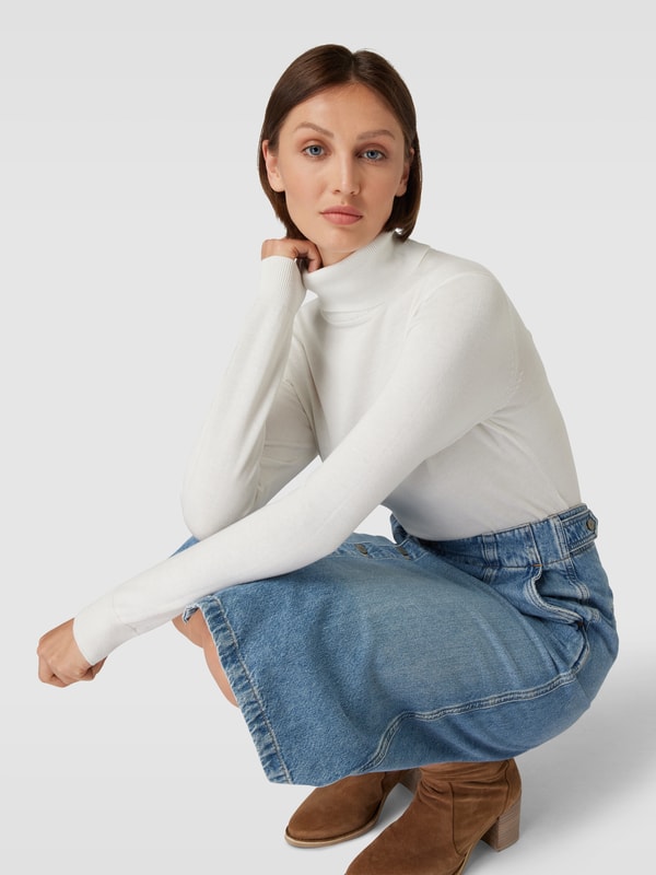 Woman in white turtleneck sweater with denim skirt